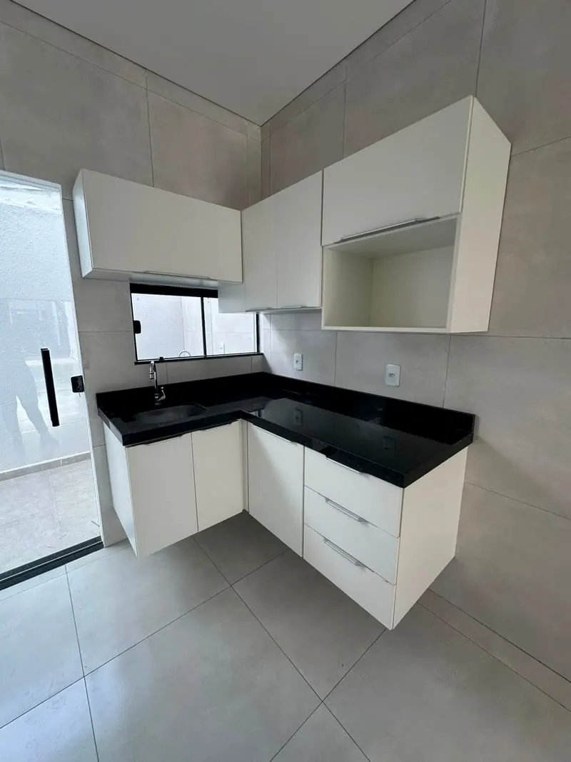 Cozinha da casa, com armários brancos e bancada de granito preto