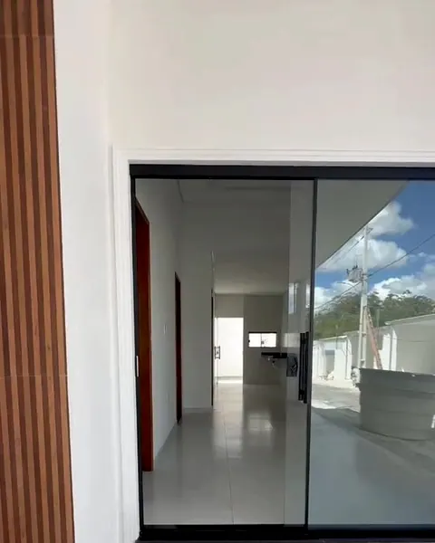 Porta de vidro de correr da entrada da casa, com o corredor ao fundo