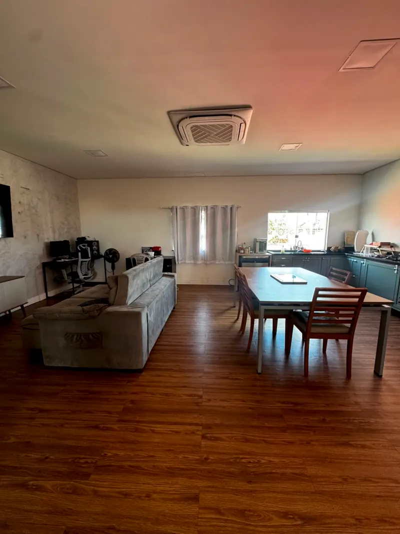 Sala ampla da casa principal, com sofá, mesa de jantar e piso de madeira