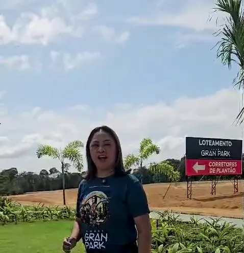 Ângela ao lado da placa do loteamento Gran Park, com corretores de plantão