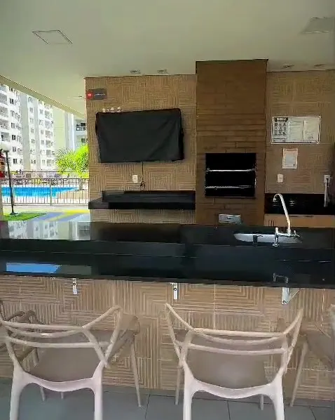 Espaço gourmet do Vista das Paineiras, com churrasqueira, bancada e a piscina ao fundo