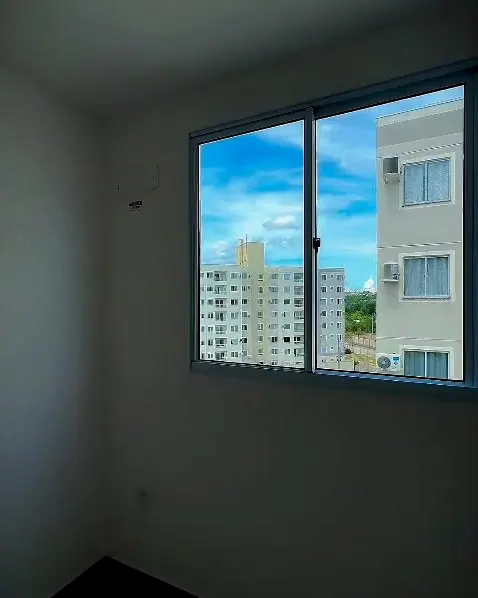Quarto do apartamento, com janela e vista para os prédios do condomínio